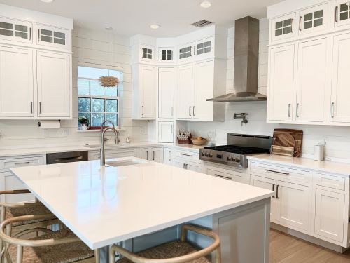 White modern kitchen with cabinets and island sink. 